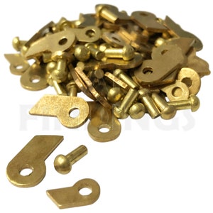 May include: A pile of brass-colored metal hardware, including small round pieces with a hole in the center, and larger pieces with a curved shape and a hole in the center.