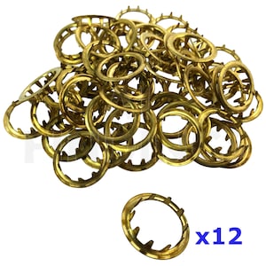May include: A pile of 12 gold-coloured metal rings with a serrated edge. The rings are approximately 2.5 cm in diameter. x12