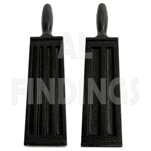 May include: Two black cast iron molds with handles. Each mold has five rectangular cavities.