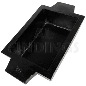 May include: A black metal casting mold with a rectangular shape and two handles. The mold is marked with the number "50".
