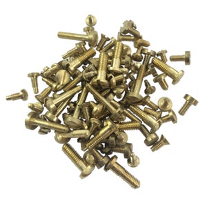 May include: A large pile of brass screws with a rounded head and a slotted drive. The screws are all the same size and are arranged in a random pattern.