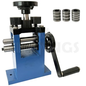 May include: A blue metal rolling mill with a black handle and gears. Three metal rollers are visible, along with a large black wheel and a handle. The mill is designed for metalworking and jewelry making.