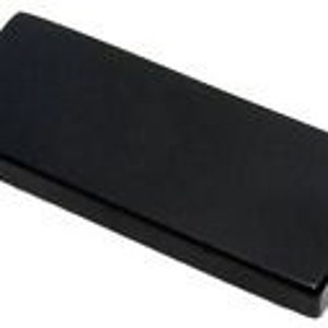 以下が含まれることがあります： 長方形の黒い物体で、角が丸みを帯びています。表面は滑らかで光沢があります。細長い形状で、蓋、ベース、または装飾要素の可能性があります。寸法は確認できません。