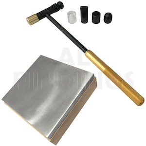 May include: A gold and black metal hammer with a wooden handle and a square metal anvil. The hammer has a rubber head and comes with a set of four different shaped rubber tips.