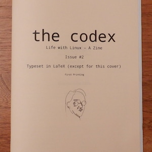 May include: A zine titled "the codex" with the subtitle "Life with Linux." The cover is off-white with black text and a line drawing of a person wearing glasses. The text includes "Issue #2" and "Typeset in LaTeX (except for this cover)."