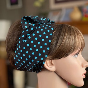 Peut inclure: Un bandeau noir &agrave; pois bleus est nou&eacute; sur la t&ecirc;te d'un mannequin. Le bandeau est en tissu et pr&eacute;sente un motif r&eacute;p&eacute;titif de pois bleu clair sur fond noir. Le bandeau est nou&eacute; en forme de n&oelig;ud sur le dessus de la t&ecirc;te.