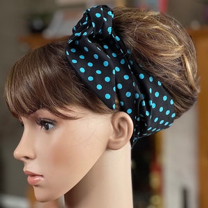 Peut inclure: Un foulard noir &agrave; pois bleu clair est nou&eacute; autour de la t&ecirc;te d'un mannequin. Le foulard est nou&eacute; sur le dessus, mettant en valeur le motif. Le mannequin a les cheveux bruns et est vu de profil.