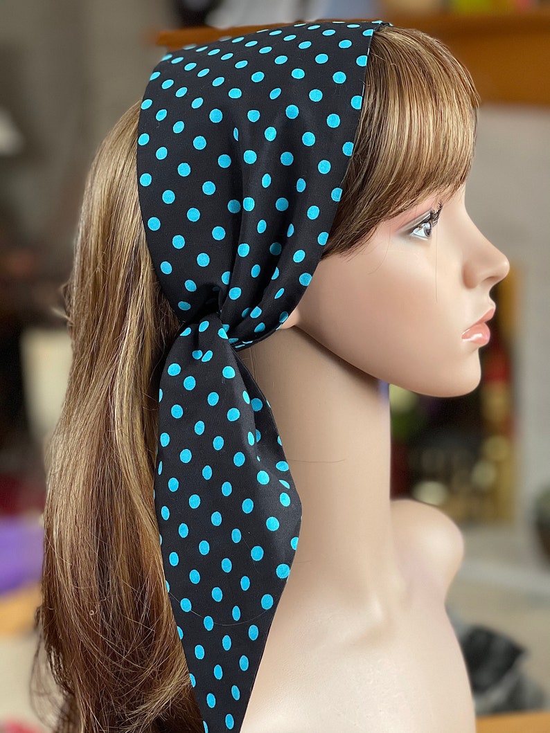 Peut inclure: Un foulard noir orn&eacute; de pois bleu clair. Le foulard est nou&eacute; &agrave; la nuque, les extr&eacute;mit&eacute;s pendantes. Le foulard est pr&eacute;sent&eacute; sur une t&ecirc;te de mannequin avec des cheveux ch&acirc;tain clair.