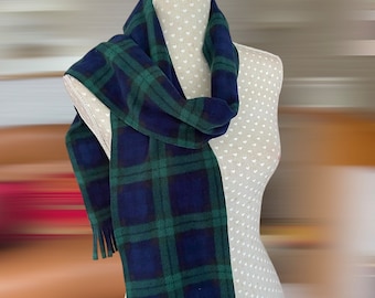 May include: A blue and green plaid scarf with fringe detail is draped over a mannequin. The scarf is made of a soft material and features a classic tartan pattern. The scarf is a winter accessory.