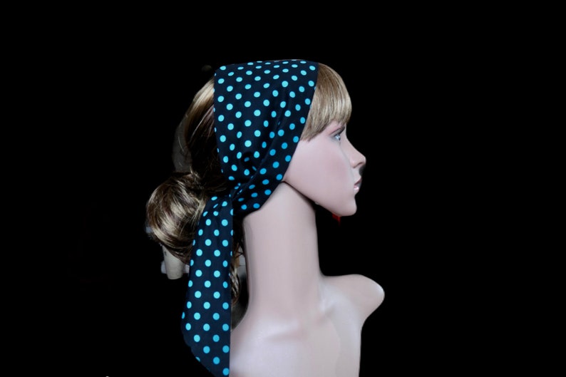 Peut inclure: Un foulard noir &agrave; pois bleu clair. Le foulard est nou&eacute; autour de la t&ecirc;te et du cou d'un mannequin, avec les extr&eacute;mit&eacute;s pendantes. Le fond est noir.