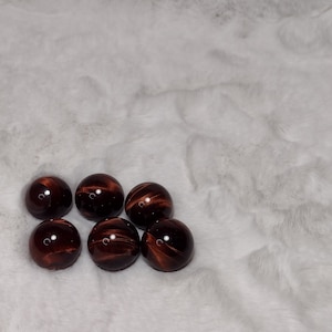 May include: Six round, red tiger's eye beads with a brown and gold pattern.