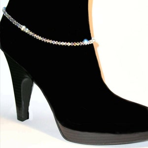 May include: A black ankle boot with a crystal ankle bracelet. The bracelet is made of small, clear crystals that sparkle in the light.