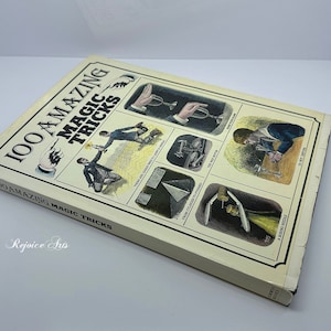 May include: A vintage book titled "100 Amazing Magic Tricks" with illustrations of magic tricks on the cover. The book is in a light brown color with black text.
