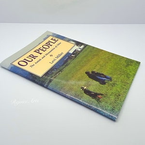 May include: A book titled "Our People: The Amish and Mennonites of Ohio" by Levi Miller. The cover features a photograph of a green field with people walking in the distance.