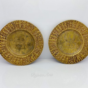 May include: Two small, round, gold-colored brass plates with an embossed design. The plates feature a depiction of the Hagia Sophia mosque in Istanbul, Turkey. The text "AYA SOFİYA" is inscribed on the plates.