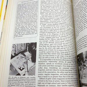 Puede incluir: Una mujer est&aacute; sentada en un escritorio dibujando una ilustraci&oacute;n en blanco y negro de un joven con una espada. La ilustraci&oacute;n est&aacute; en un trozo de papel sobre un escritorio de madera clara. La mujer lleva una camisa blanca y una falda oscura.