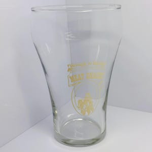 May include: A clear glass drinking glass with a gold design that reads "Rough N Ready" and "Meat Snacks".