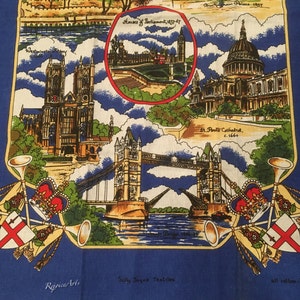 May include: A blue tea towel with a colorful illustration of famous London landmarks, including the Houses of Parliament, Tower Bridge, and St. Paul's Cathedral. The text "Houses of Parliament 1837-47", "St. Paul's Cathedral, c.1666", "Tower Bridge 1886-94", "Rejpice Arts", "Sally Jayne Textiles", and "all cotton - British Made" is printed on the towel.