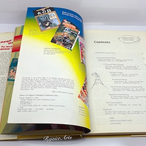 Puede incluir: Un libro abierto con una cubierta a rayas amarillas, rojas y blancas. El libro se titula "Manga! El mundo del c&oacute;mic japon&eacute;s". La p&aacute;gina de contenido del libro es visible, enumerando temas como "Mil millones de mangas", "El arte del c&oacute;mic manga", "El esp&iacute;ritu de Jap&oacute;n", "Flores y sue&ntilde;os", "El animal econ&oacute;mico en el trabajo y en el juego", "La regulaci&oacute;n es rampante", "&iquest;Hay sala de espera?", "La industria del c&oacute;mic", "El futuro", "La nueva generaci&oacute;n visual", "&Iacute;ndice", "M&aacute;s sobre los c&oacute;mics japoneses", "&Uacute;ltimas palabras".