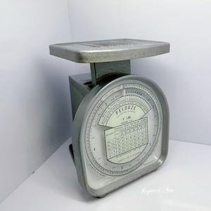 May include: Vintage Pelouze postal scale, model Y-8, in a silver-gray finish. The scale features a circular dial with weight measurements and postal rate information. The platform is rectangular, and the base is a boxy shape.