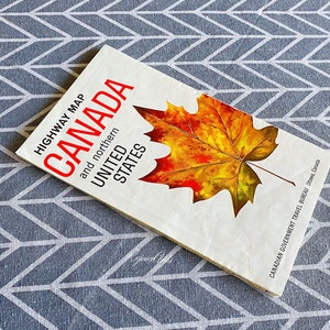 Peut inclure: Une carte routière vintage du Canada et du nord des États-Unis, avec une feuille d'érable rouge, jaune et verte sur la couverture. La carte est publiée par l'Office national du tourisme du Canada, Ottawa, Canada.