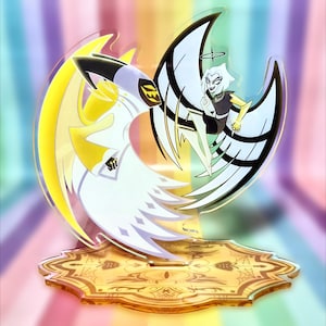 May include: A clear acrylic stand featuring a cartoon character with white wings and a halo. The character is depicted in black, white, and yellow. The stand has a gold-colored base with an ornate design, set against a rainbow background.