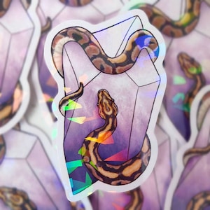 Może przedstawiać: Naklejka przedstawiająca brązowo-czarną węża owiniętą wokół fioletowego, tęczowego kryształu. Kryształ ma geometryczny kształt i jest obwiedziony białym kolorem.