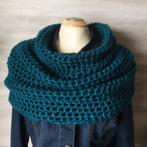 May include: Teal blue crocheted cowl neck scarf. The scarf is made with a textured stitch pattern.