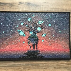 May include: A painting of a tree with a dark blue trunk and branches, with many small, light blue circles around it. The tree is standing on a dark blue surface with a red and orange sunset in the background. The tree has a large, light blue sphere at the top, and many smaller light blue spheres on the branches.