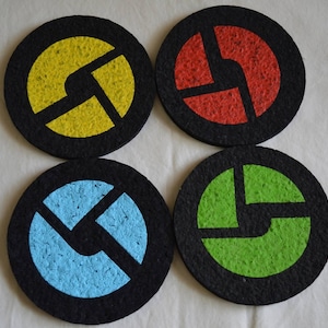 May include: Four round coasters with a black background and a stylized logo in the centre. The logos are yellow, red, blue, and green.