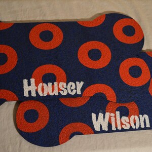 May include: Two blue and red dog bone shaped doormats with the names "Houser" and "Wilson" printed in white.