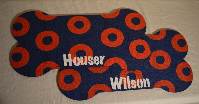 May include: Two blue and red dog bone shaped doormats with the names "Houser" and "Wilson" printed in white.