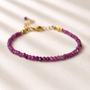 Peut inclure: Un bracelet délicat composé d'un rang continu de petites perles de pierres précieuses facettées de couleur magenta profond. Le bracelet comprend une chaînette d'extension en métal doré avec un fermoir mousqueton et une petite perle assortie.