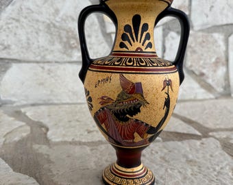 May include: A small, ceramic Greek amphora with black handles and a black and red geometric design. The amphora is decorated with a black and red image of a woman holding a flower. The text "ΕΡΜΗΣ" is written on the amphora.
