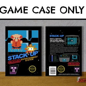 May include: A black Nintendo Entertainment System game case for the game Stack-Up. The front features pixel art of a character and the title. The back displays game information, screenshots, and the Nintendo logo. Text reads GAME CASE ONLY.