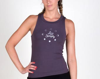May include: A woman wearing a gray tank top with the text "Live Simply" and a black skirt. The tank top has a circle design with white dots.
