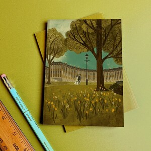 Op de afbeelding: Een vintage-stijl illustratie van een rij gebouwen met een stel dat er voor loopt. De gebouwen zijn geschilderd in tinten bruin en geel, en het stel is gekleed in bruin en wit. De scène speelt zich af in een park met een groen gazon en gele bloemen.
