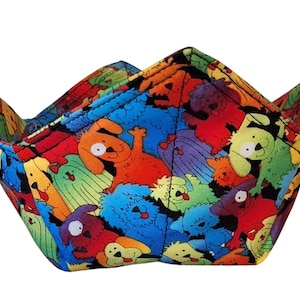 May include: A colourful fabric bowl with a pattern of cartoon dogs in various colours and poses. The bowl is folded and ready to be used.
