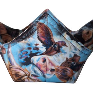 May include: A blue and white fabric bowl with a cow print design. The bowl is shaped like a crown and has a wide opening.