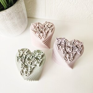 May include: Three heart-shaped boxes with a layered design. Each box is decorated with a pattern of butterflies. The boxes are in shades of pink and green.