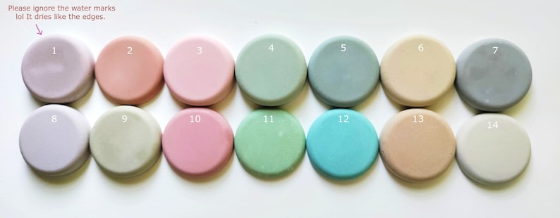 May include: Fourteen round, flat, smooth, painted discs in various shades of pink, gray, beige, and green. The discs are numbered 1 through 14.