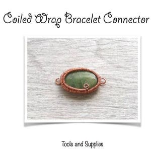 May include: A coiled wire bracelet connector with a green oval cabochon. The connector is made of copper wire and is approximately 24mm x 14mm x 3mm. The connector is shown on a light brown surface.