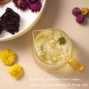 May include: A glass teapot filled with white flower tea, with a yellow handle, sits on a light pink surface. Dried flowers are arranged around the teapot. The text reads: "Every Sip of Flower Tea Counts... Skin Care & Calming & Sleep Aid."