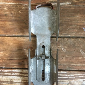 May include: A pair of vintage metal ice skates with a silver finish and a red leather strap. The skates have a metal adjustment knob and are in good condition.