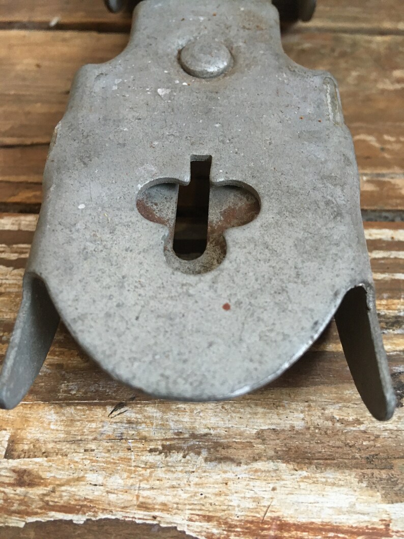 May include: Close-up of a silver metal object with a keyhole shaped like a clover. The object has a rounded shape and a smooth surface.