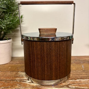 May include: Vintage ice bucket with a wood grain finish, stainless steel trim, and a wooden handle. The lid is stainless steel with a small wooden handle. The bucket has a cylindrical shape and a metal handle.