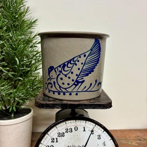 May include: A white ceramic mug with a black handle and the text "But First, Coffee" in a black, handwritten-style font. The mug is on a white surface.