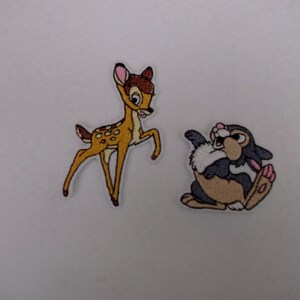 May include: Two embroidered iron-on patches featuring Disney characters. The first patch is a brown and white deer with pink ears. The second patch is a brown and grey rabbit with pink ears.