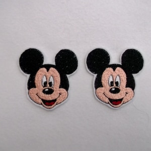 May include: Two iron-on patches featuring Mickey Mouse's face. The patches are black, white, and red.