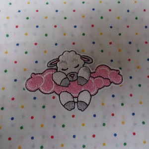 May include: An embroidered patch featuring a white sheep sleeping on a pink cloud. The sheep has its eyes closed and a small, curled tail.